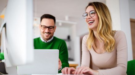A man and a woman look at information on a notebook.
