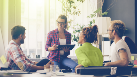 An employee sits with three customers in AKQUINET's office and advises on the correct handling of company data.